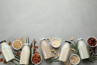 Different vegan milks and ingredients on light grey table, flat lay. Space for text