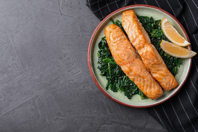 Tasty salmon with spinach and lemon on grey table, flat lay. Space for text