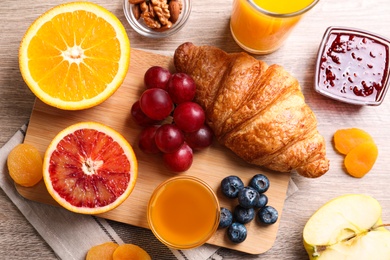 Delicious breakfast with croissant on wooden table, flat lay