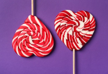 Sweet heart shaped lollipops on purple background, flat lay. Valentine's day celebration