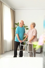 Elderly man and his wife with walking frame indoors