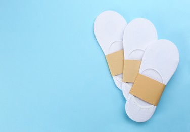White cotton socks on light blue background, flat lay. Space for text