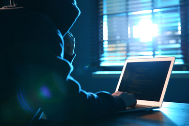 Hacker with laptop in dark room. Cyber crime