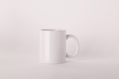 Blank white ceramic mug on light background