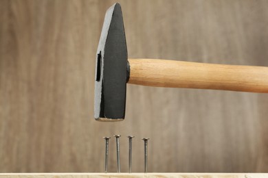 Photo of Hammering nail into plank against wooden background
