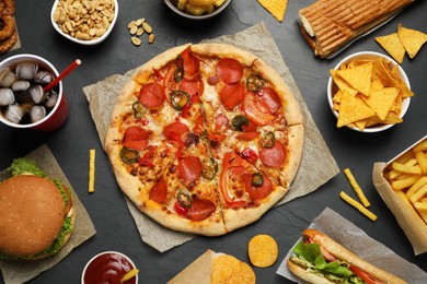 Photo of Pizza, burger and other fast food on black table, flat lay