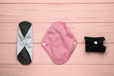 Many reusable cloth menstrual pads on pink wooden table, flat lay
