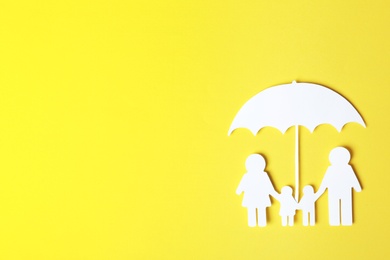 Paper silhouette of family under umbrella and space for text on color background, top view. Life insurance concept