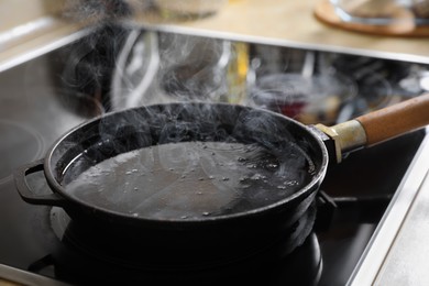 Photo of Frying pan with hot used cooking oil on stove