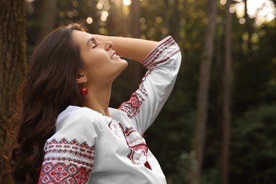 Photo of Beautiful woman in embroidered shirt outdoors, space for text. Ukrainian national clothes