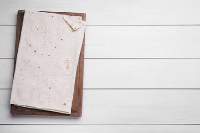 Photo of Delicious Armenian lavash on white wooden table, top view. Space for text