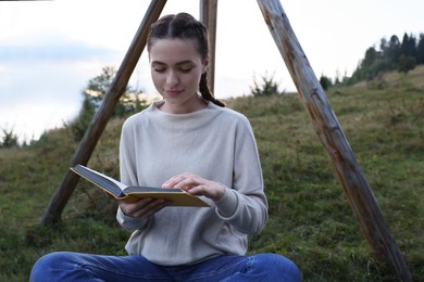 Beautiful young woman reading book in evening outdoors