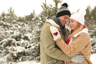Beautiful happy couple in snowy forest on winter day