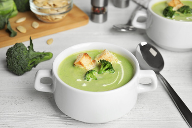 Delicious broccoli cream soup with croutons served on white wooden table