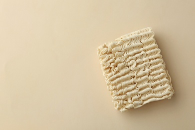 Block of quick cooking noodles on color background, top view. Space for text
