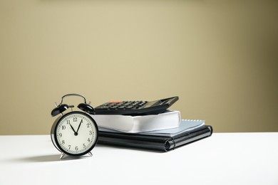 Alarm clock and office stationery on white table against beige background, space for text. Time management