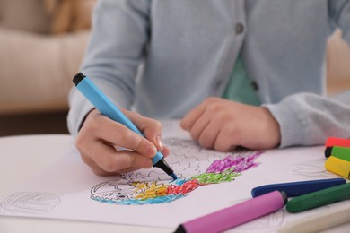 Child coloring drawing at table in room, closeup