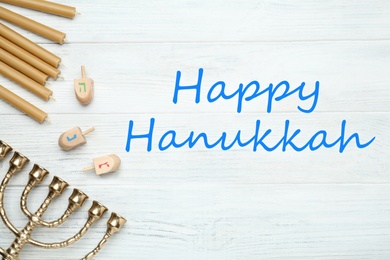 Happy Hanukkah. Traditional menorah, candles and dreidels on white wooden table, flat lay 