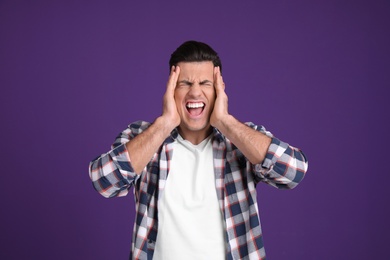 Portrait of stressed man on purple background