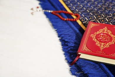 Muslim prayer beads, Quran, rug and space for text on light background