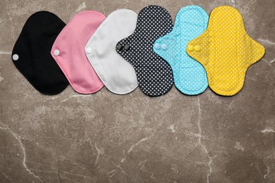Many reusable cloth menstrual pads on brown table, flat lay. Space for text