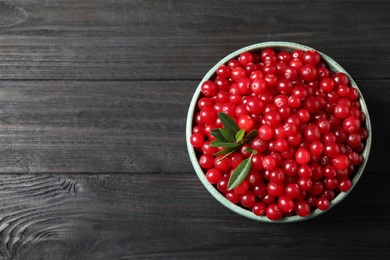 Photo of Tasty ripe cranberries on black wooden table, top view. Space for text