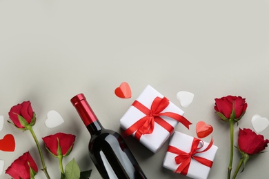 Beautiful gift boxes, roses and wine on grey background, flat lay with space for text. Valentine's day celebration