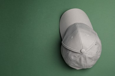 Stylish grey baseball cap on dark green background, top view. Space for text