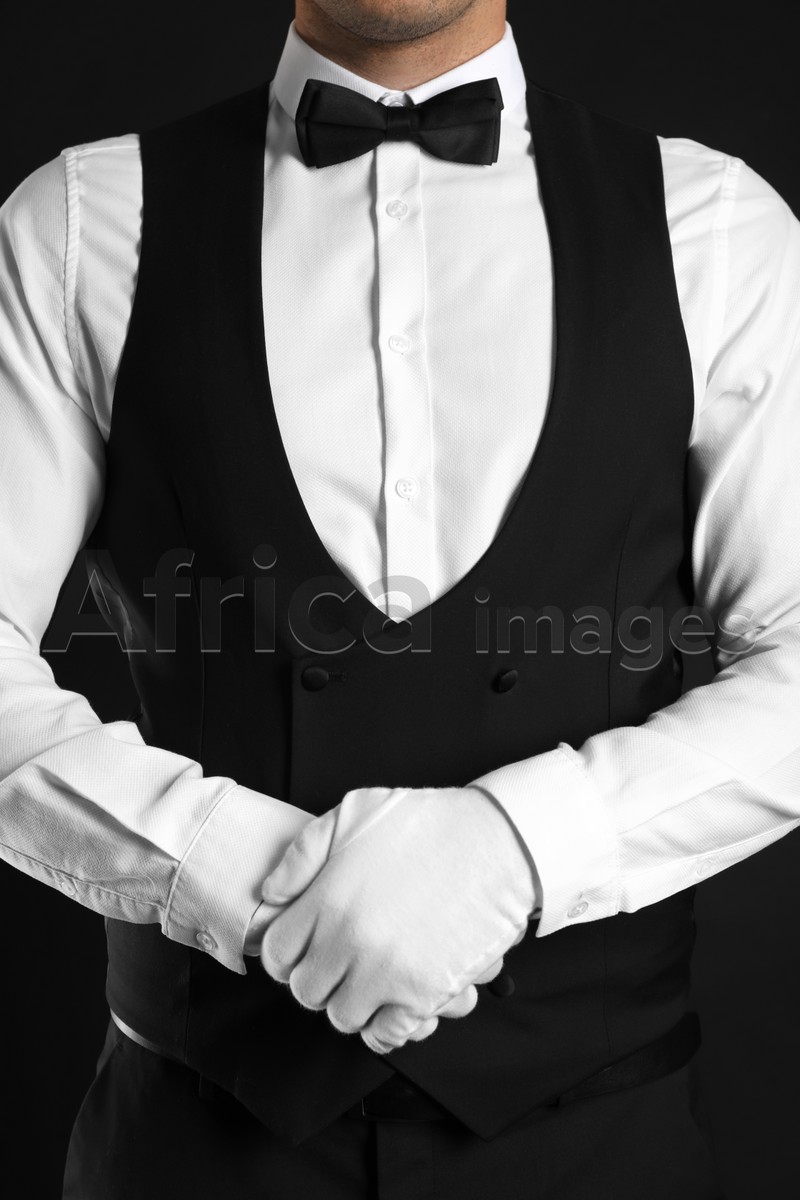 Butler in elegant uniform on black background, closeup