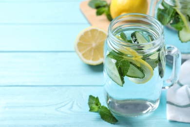 Refreshing water with cucumber, lemon and mint on light blue wooden table, closeup. Space for text