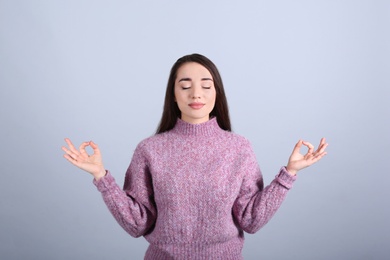 Young woman meditating on grey background. Stress relief exercise