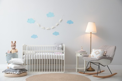 Photo of Stylish baby room interior with crib and rocking chair