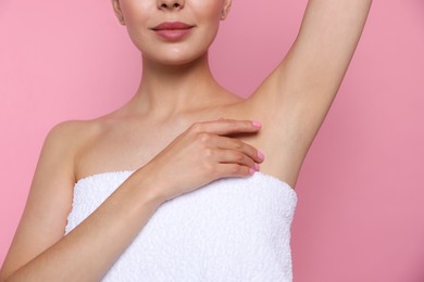 Young woman showing smooth skin after epilation on pink background, closeup