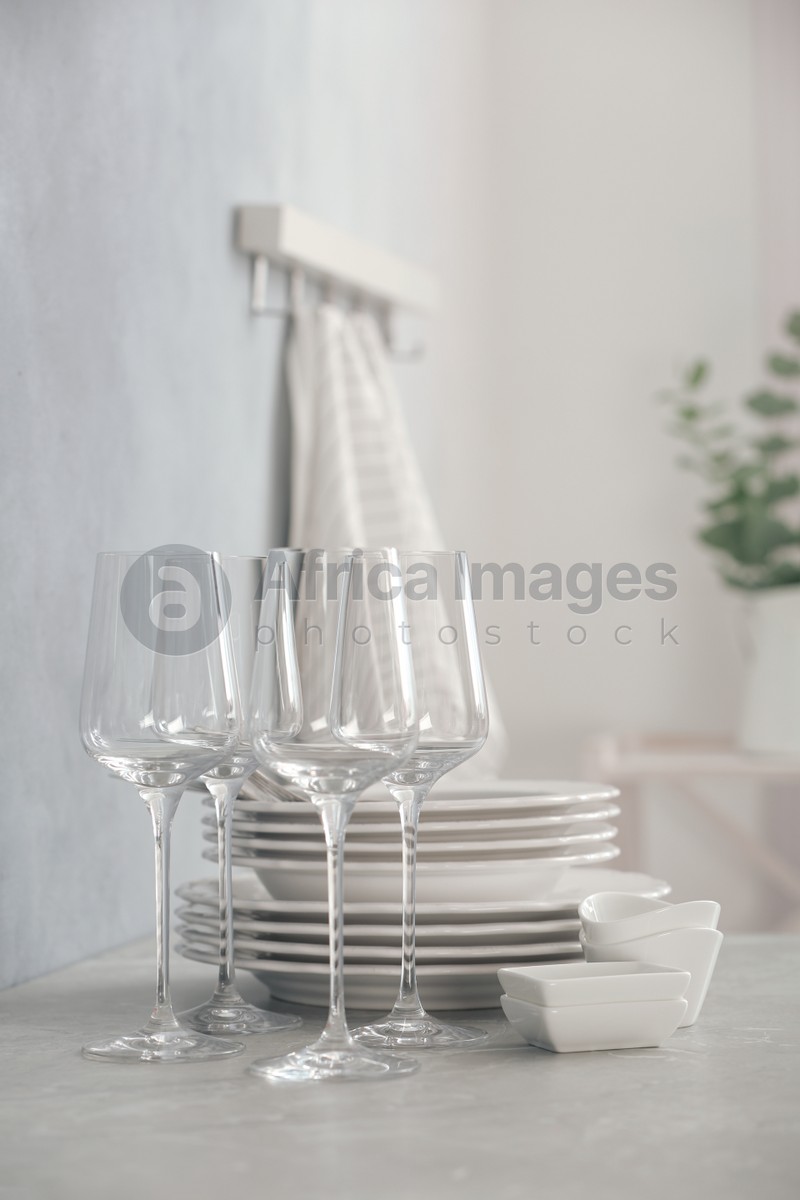 Photo of Set of clean dishware and wineglasses on grey table indoors. Space for text