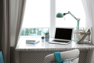 Comfortable workplace with laptop on window sill at home