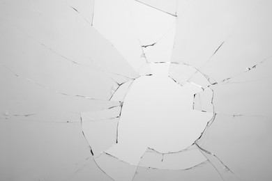 Closeup view of broken glass with cracks on white background