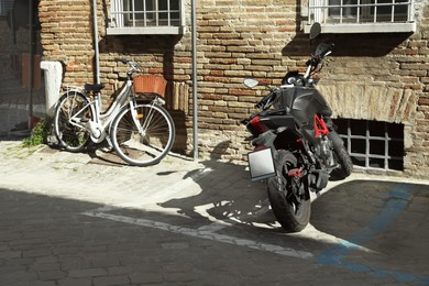 Photo of Bicycle and motorbike parked near building on sunny day