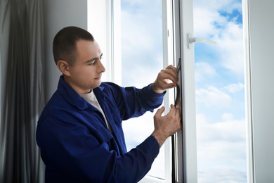 Construction worker putting sealing foam tape on window indoors