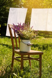 Beautiful bouquet with field flowers on chair outdoors, space for text