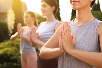 Young women practicing yoga outdoors on sunny day, closeup