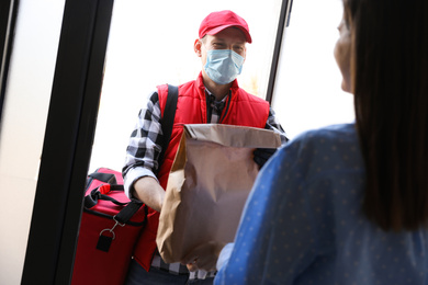 Courier giving order to woman at entrance. Delivery service during coronavirus quarantine