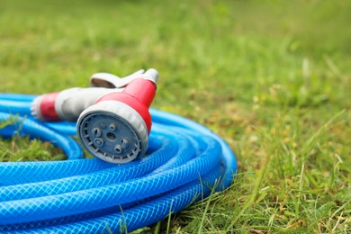 Photo of Watering hose with sprinkler on green grass outdoors, closeup. Space for text
