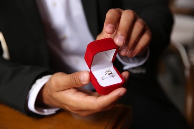 Photo of Man with engagement ring making proposal at table, closeup