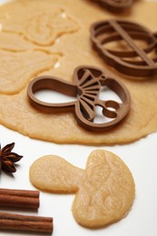 Photo of Cookie cutters and dough on white table, closeup
