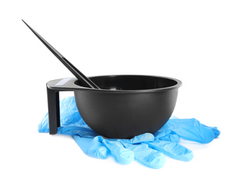 Bowl with hair dye, brush and rubber gloves on white background