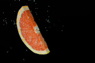 Slice of grapefruit in sparkling water on black background, space for text. Citrus soda