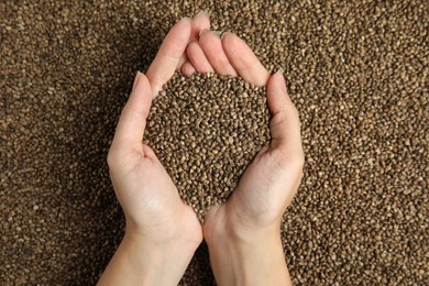 Woman holding pile of hemp seeds, top view