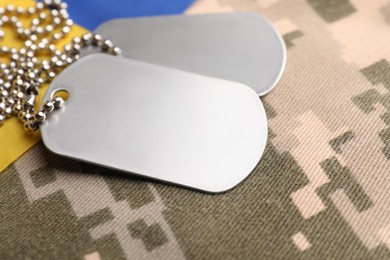 Military ID tags and Ukrainian flag on pixel camouflage, closeup