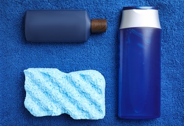 Bottles and bast wisp on blue towel, flat lay. Men's cosmetics