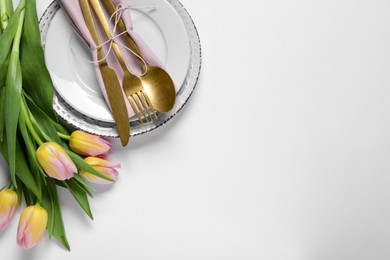Photo of Stylish table setting with cutlery and tulips on white background, flat lay. Space for text